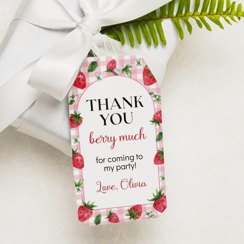 May include: A rectangular gift tag with a pink and white gingham pattern, decorated with watercolor strawberries and small white flowers. The text reads: THANK YOU berry much for coming to my party! Love, Olivia, in black and red script fonts.