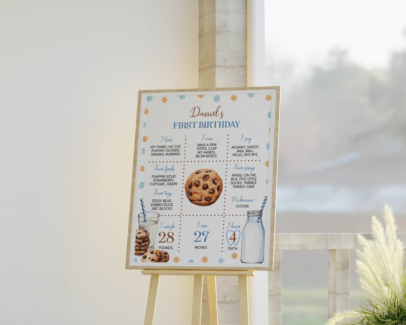 May include: A blue and brown printable first birthday sign for a boy named Daniel. The sign features a cookie graphic and lists the child's age, weight, height, and favorite foods, toys, and songs.