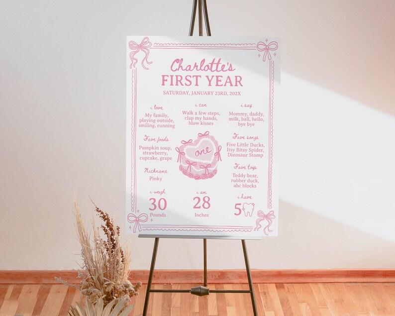 May include: A pink and white printable first birthday chart for a baby girl named Charlotte. The chart includes details about her first year, such as her weight, height, favorite foods, and songs. It also includes a cute illustration of a cake with the number one on it.