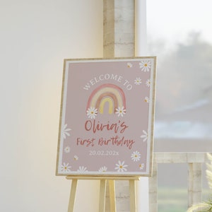May include: Welcome to Olivia's First Birthday sign with a rainbow and daisies on a light pink background. The date 20.02.202X is printed below the text.