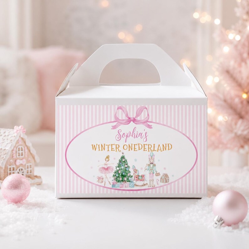 May include: A white gable box with a light pink striped pattern. The front features an oval frame with a pink bow, the text "Sophia's WINTER ONEDERLAND," and illustrations of a ballerina, a Christmas tree, a rocking horse, and a nutcracker.