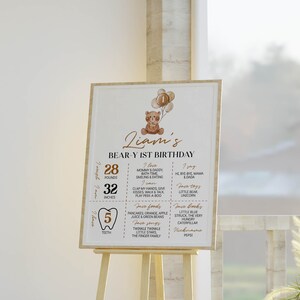 Puede incluir: Un cartel rectangular de cumplea&ntilde;os con una ilustraci&oacute;n de un oso de peluche marr&oacute;n con globos, el texto Liam's BEAR-Y 1ST BIRTHDAY y secciones que detallan 28 libras, 32 pulgadas, 5 dientes, adem&aacute;s de comidas, libros, canciones y actividades favoritas.