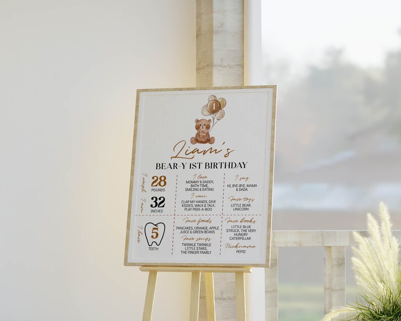 Puede incluir: Un cartel rectangular de cumplea&ntilde;os con una ilustraci&oacute;n de un oso de peluche marr&oacute;n con globos, el texto Liam's BEAR-Y 1ST BIRTHDAY y secciones que detallan 28 libras, 32 pulgadas, 5 dientes, adem&aacute;s de comidas, libros, canciones y actividades favoritas.