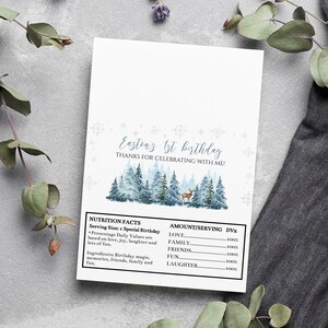May include: A rectangular white card featuring the text Easton's 1st birthday, thanks for celebrating with me, and a watercolor forest scene with a deer. Below is a nutrition facts label listing love, family, friends, fun, and laughter.