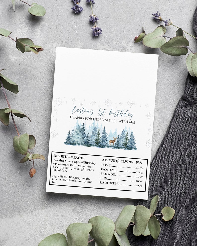 May include: A rectangular white card featuring the text Easton's 1st birthday, thanks for celebrating with me, and a watercolor forest scene with a deer. Below is a nutrition facts label listing love, family, friends, fun, and laughter.