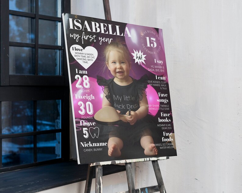 May include: A pink and black first birthday poster for a baby girl named Isabella. The poster features a photo of the baby girl, along with details about her first year, including her height, weight, and favorite things. The poster is decorated with pink balloons and hearts.