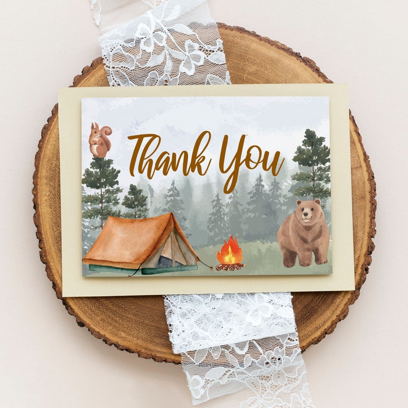 May include: A thank you card with a watercolor illustration of a forest scene with a tent, a campfire, a bear, and a squirrel. The text "Thank You" is written in brown letters.