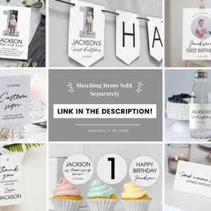 Op de afbeelding: Een set witte eerste verjaardagspapierwaren inclusief een foto-uitnodiging, banner, welkomstbord, waterfleslabel, bedankkaartje, cupcake-toppers en een tentkaartje voor eten, allemaal met zwarte tekst en minimalistische typografie.