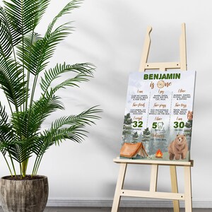 May include: A rectangular milestone sign for a one-year-old named Benjamin, featuring a forest theme with a bear, tent, and campfire. The text lists milestones including weight of 32 pounds, height of 30 inches, five teeth, and favorite things.