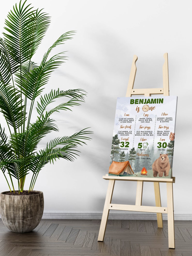 May include: A rectangular milestone sign for a one-year-old named Benjamin, featuring a forest theme with a bear, tent, and campfire. The text lists milestones including weight of 32 pounds, height of 30 inches, five teeth, and favorite things.