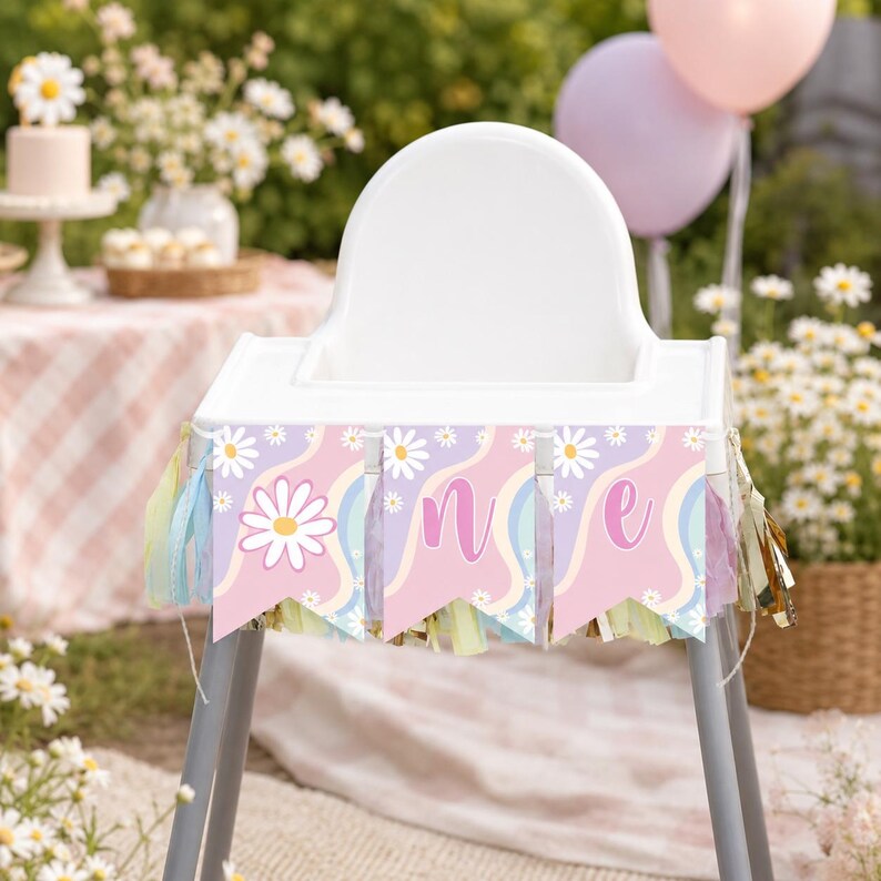 Op de afbeelding: Een witte kinderstoel versierd met een vlaggenlijn met een pastelroze, paars en blauw golvend patroon met witte madeliefjes. De banner toont de letters O, N en E op drie afzonderlijke vlaggetjes, geaccentueerd met hangende kwastjes.