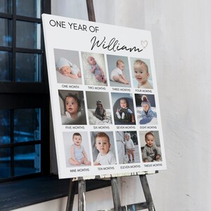 May include: A white rectangular photo collage board titled ONE YEAR OF William with a heart icon. It features twelve individual square photographs of a baby arranged in three rows, each labelled with the corresponding age from one to twelve months.