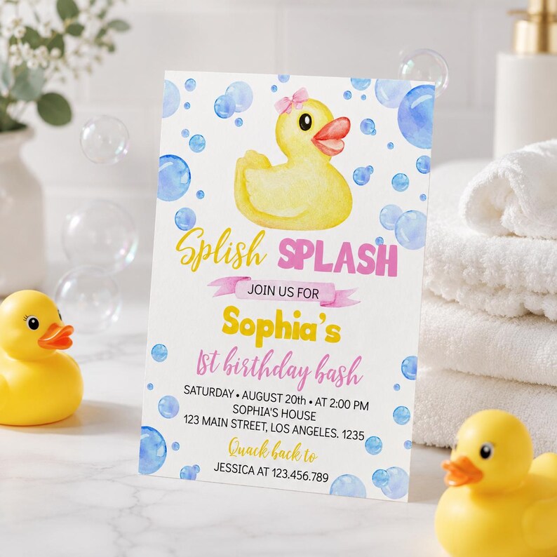 May include: A rectangular birthday invitation card featuring a yellow rubber duck with a pink bow, blue watercolor bubbles, and the text Splish Splash Join us for Sophia's 1st birthday bash Saturday August 20th at 2:00 PM Sophia's house 123 Main Street.
