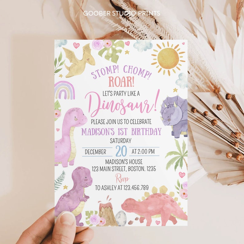 May include: A rectangular birthday invitation card featuring watercolor illustrations of dinosaurs, a volcano, a sun, clouds, and flowers. The text reads: STOMP! CHOMP! ROAR! LET'S PARTY LIKE A DINOSAUR! PLEASE JOIN US TO CELEBRATE MADISON'S 1ST BIRTHDAY.