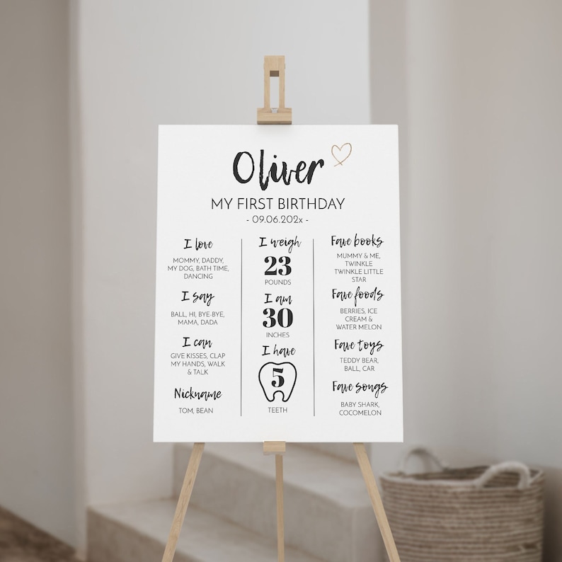 May include: A white rectangular birthday milestone sign featuring the name Oliver, the text My First Birthday, and the date 09.06.202x. The sign lists personal details including weight in pounds, height in inches, and five teeth, with black text.