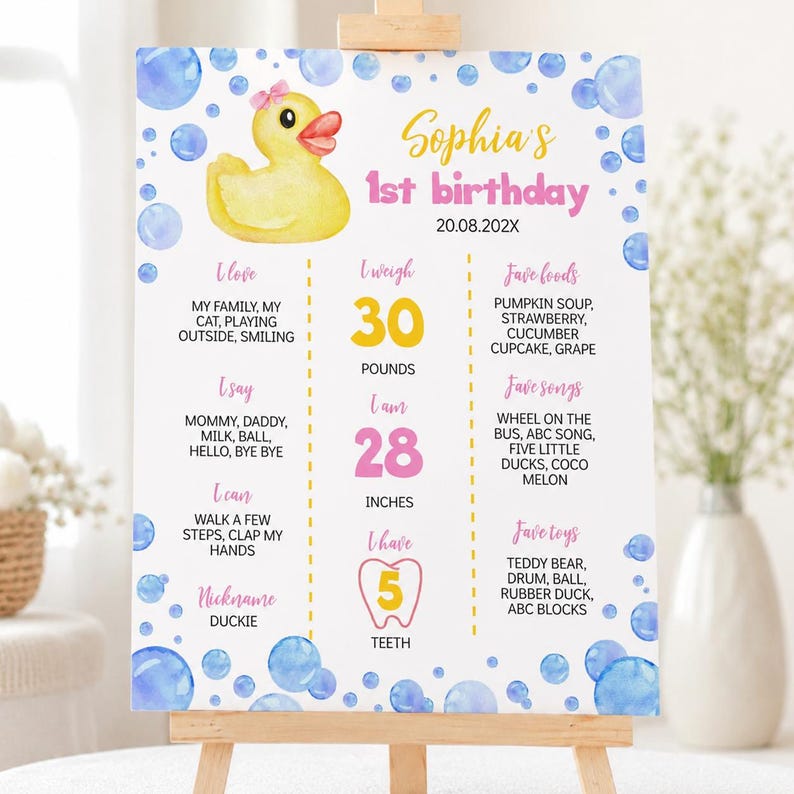May include: A white birthday milestone sign featuring a yellow rubber duck with a pink bow, blue watercolor bubbles, and pink text. It lists Sophia's 1st birthday, 20.08.202X, 30 pounds, 28 inches, 5 teeth, and various personal facts in columns.