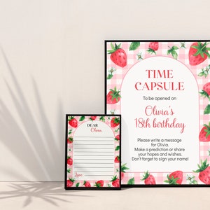 May include: Two framed signs with a pink and white gingham background and watercolor strawberry illustrations. The larger sign reads TIME CAPSULE To be opened on Olivia's 18th birthday. The smaller sign has lines for messages and reads DEAR Olivia.