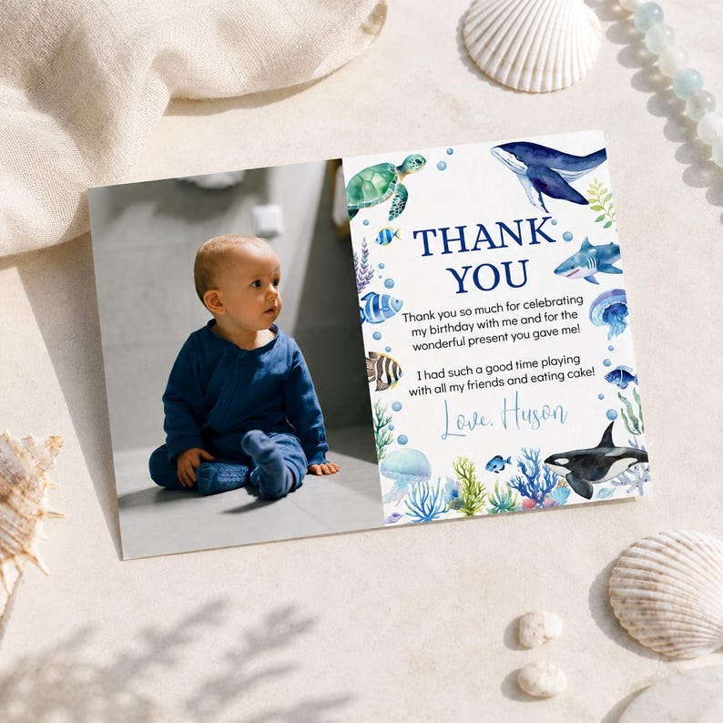 May include: A rectangular thank you card featuring a photograph of a baby in a blue outfit on the left and watercolor sea life illustrations on the right. The text reads: THANK YOU, Thank you so much for celebrating my birthday with me and for the wonderful present you gave me! I had such a good time playing with all my friends and eating cake! Love, Huson.