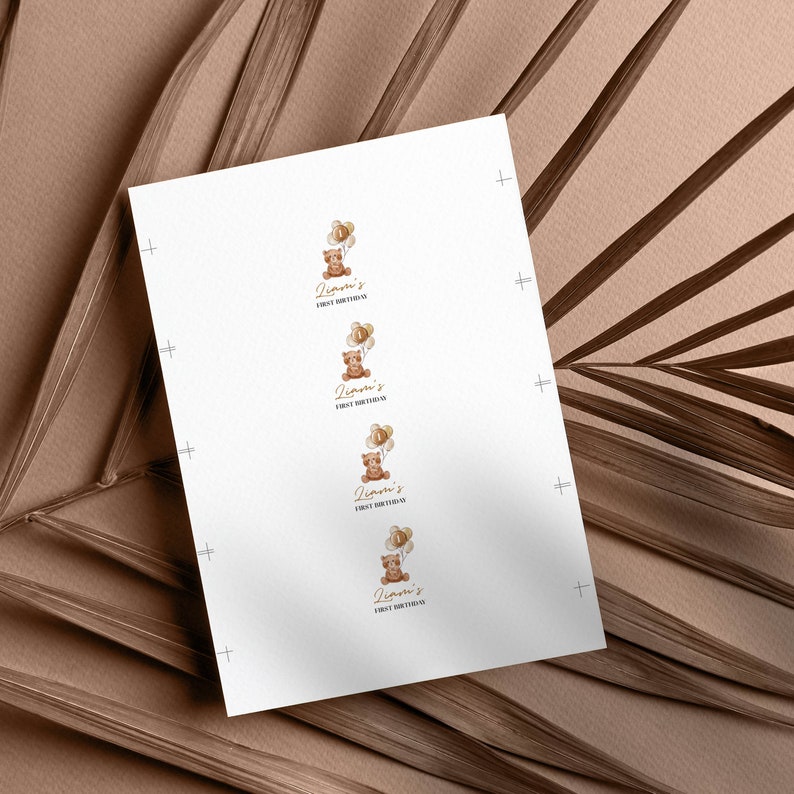 May include: A white rectangular sheet of paper featuring four identical printed designs arranged in a vertical column. Each design displays a brown teddy bear holding a cluster of beige balloons with the number one, and the text Liam's FIRST BIRTHDAY.