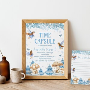 May include: A framed sign and a matching card featuring blue watercolor illustrations of fairies, pine trees, and mushroom houses. The sign reads: TIME CAPSULE To be opened when Amanda turns 18. Please write a message for Amanda.