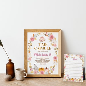 K&ouml;nnte beinhalten: Ein gerahmtes Schild mit einem Blumen- und K&uuml;rbiskranz um den Text TIME CAPSULE TO BE OPENED WHEN Olivia turns 18 sowie Anweisungen. Daneben liegt eine passende linierte Karte mit dem Text DEAR Olivia und Love.