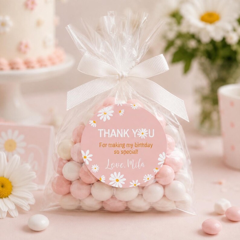 May include: A clear plastic favor bag filled with round white and light pink candies, tied with a white ribbon. A circular sticker on the front features a pink background with white daisy illustrations and the text: THANK YOU For making my birthday so special! Love, Mila.