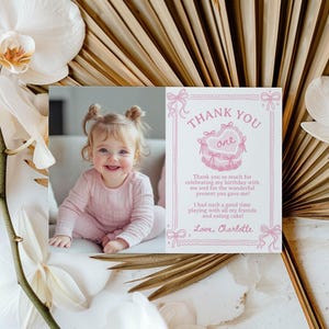 Pu&ograve; includere: Un biglietto di ringraziamento rosa e bianco con una foto di una bambina. Il biglietto dice "Grazie" e "uno" in un cuore rosa. Il testo dice "Grazie mille per aver festeggiato il mio compleanno con me e per il meraviglioso regalo che mi hai fatto! Mi sono divertita un mondo a giocare con tutti i miei amici e a mangiare la torta! Con affetto, Charlotte."