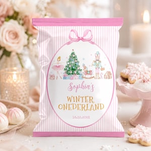 May include: A pink and white striped snack bag featuring a central oval graphic with a ballerina, a Christmas tree, a nutcracker, and a rocking horse. The text reads Sophia's WINTER ONEDERLAND 16.12.202X, topped with a pink ribbon illustration.