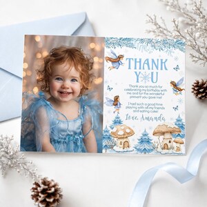 May include: A rectangular thank you card featuring a photograph of a smiling child with curly hair wearing a blue dress on the left side and blue fairy, mushroom, and snowflake illustrations with the text Thank You on the right side.