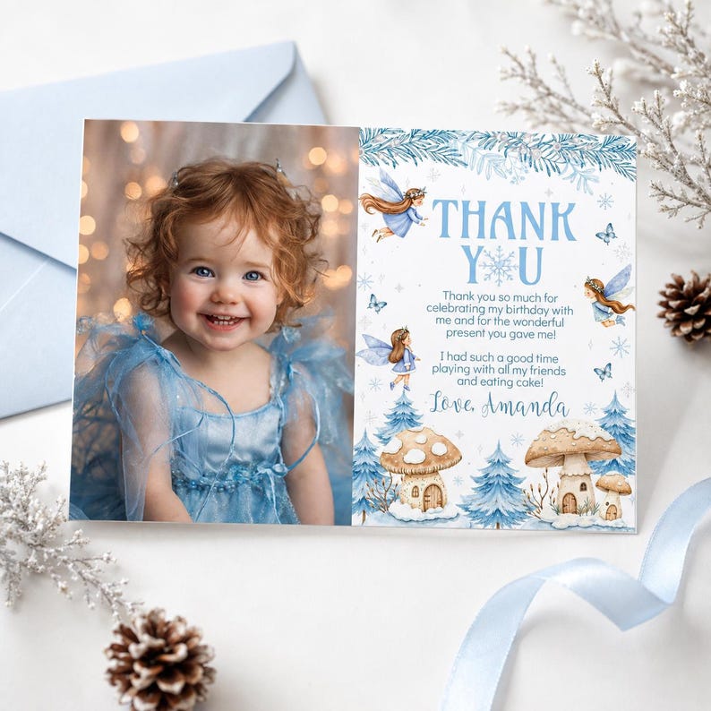 May include: A rectangular thank you card featuring a photograph of a smiling child with curly hair wearing a blue dress on the left side and blue fairy, mushroom, and snowflake illustrations with the text Thank You on the right side.
