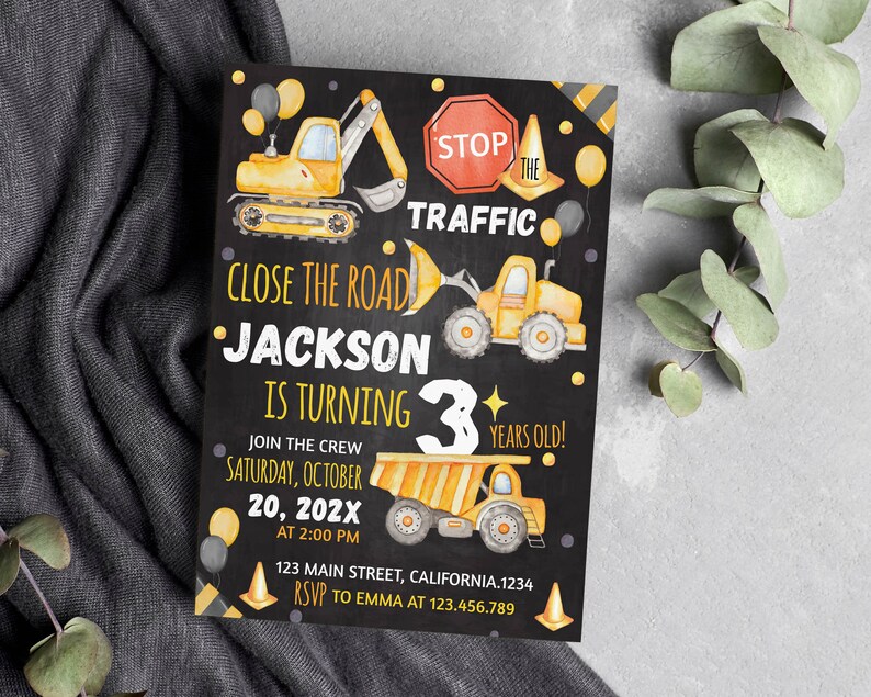 May include: A rectangular invitation card with a black background featuring yellow construction vehicles, orange traffic cones, and black and yellow balloons. The text reads: STOP THE TRAFFIC, CLOSE THE ROAD, JACKSON IS TURNING 3 YEARS OLD.
