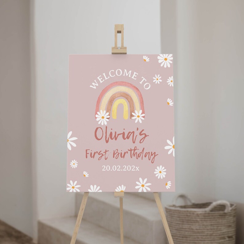 May include: A pink welcome sign with a rainbow and daisies. The sign says "Welcome to Olivia's First Birthday 20.02.202x".