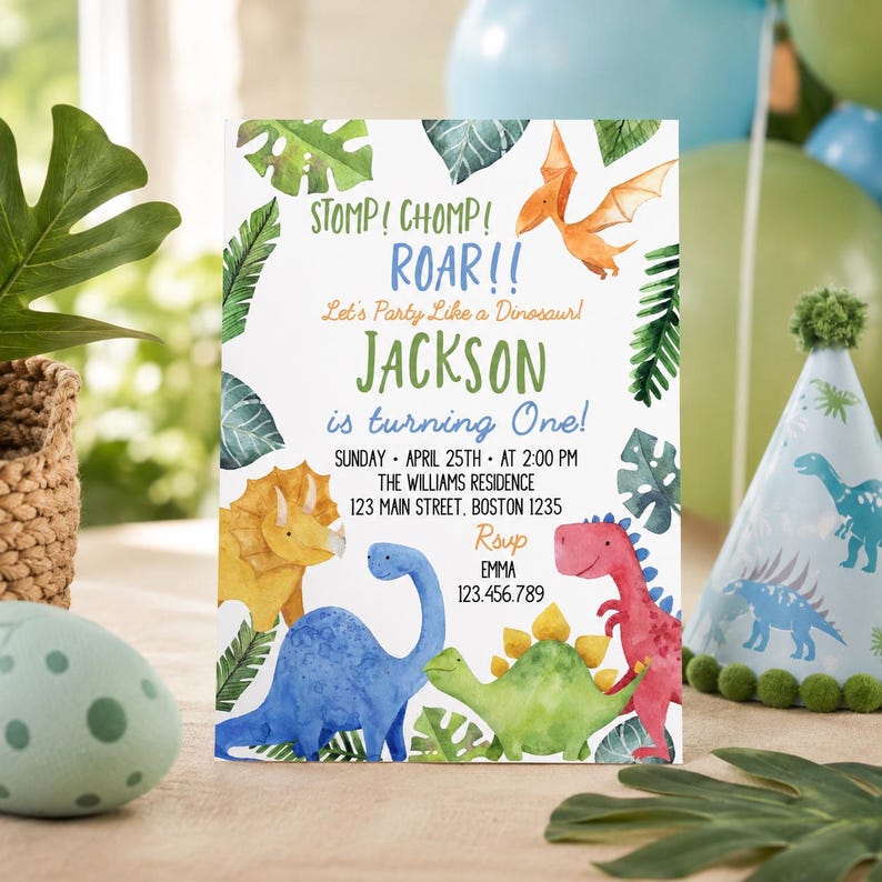 May include: A rectangular birthday invitation card featuring watercolor illustrations of various dinosaurs and tropical leaves. The text reads: STOMP! CHOMP! ROAR!! Let's Party Like a Dinosaur! JACKSON is turning One! SUNDAY APRIL 25TH AT 2:00 PM THE WILLIAMS RESIDENCE 123 MAIN STREET, BOSTON 1235 RSVP EMMA 123.456.789.