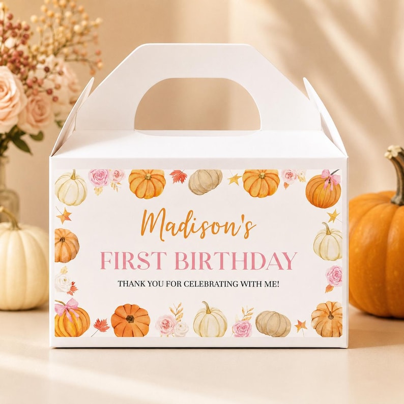 May include: A white cardboard gable box featuring a decorative border of watercolor pumpkins, pink roses, and autumn leaves. The text reads: Madison's FIRST BIRTHDAY THANK YOU FOR CELEBRATING WITH ME! The box has a top handle and a rectangular shape.