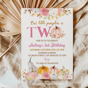 May include: A cream-coloured party invitation with the text "Our little pumpkin is TWO" and "Audrey's 2nd Birthday". The design features watercolour pumpkins, flowers, and event details. The invitation is on a cream-coloured background.