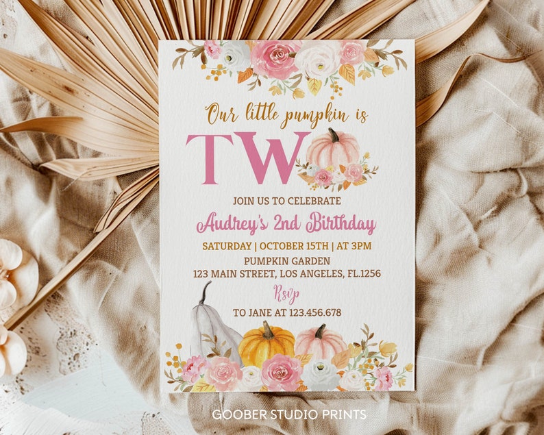 May include: A cream-coloured party invitation with the text "Our little pumpkin is TWO" and "Audrey's 2nd Birthday". The design features watercolour pumpkins, flowers, and event details. The invitation is on a cream-coloured background.