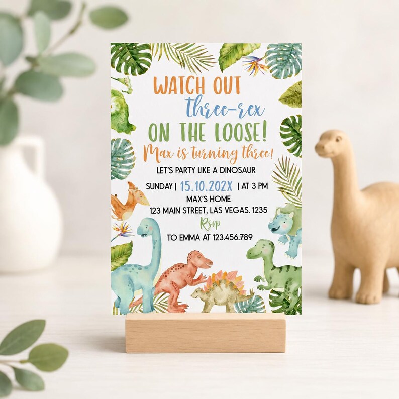 May include: A rectangular birthday invitation card featuring watercolor illustrations of various dinosaurs and tropical leaves. The text reads: WATCH OUT three-rex ON THE LOOSE! Max is turning three! LET'S PARTY LIKE A DINOSAUR SUNDAY 15.10.202X AT 3 PM.