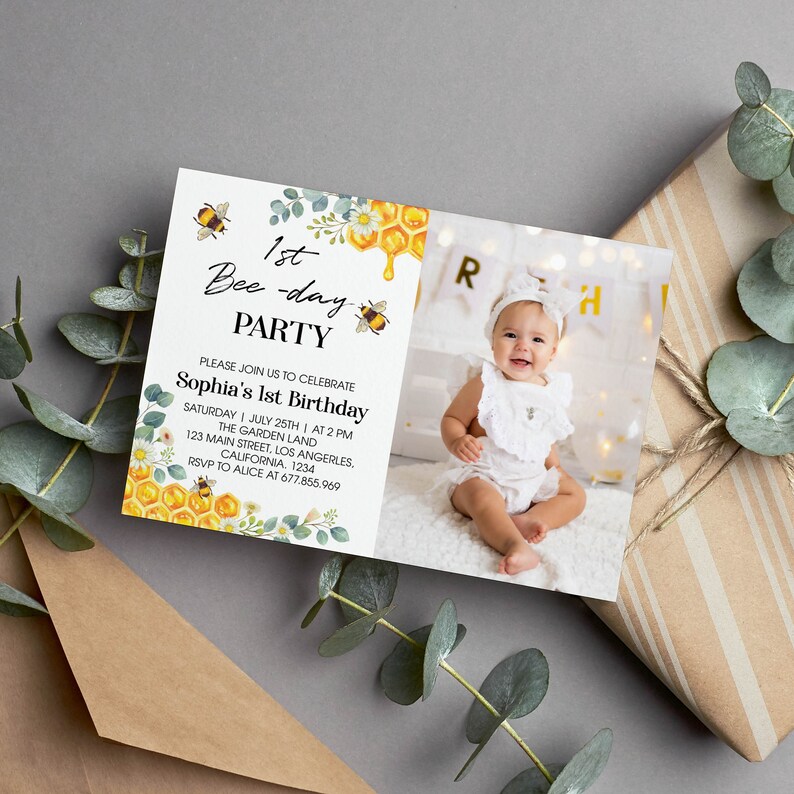 May include: A white invitation card with a bee theme. The card features a photo of a baby girl, a bee illustration, and the text "1st Bee-day Party". The invitation details include the date, time, and location of the party.
