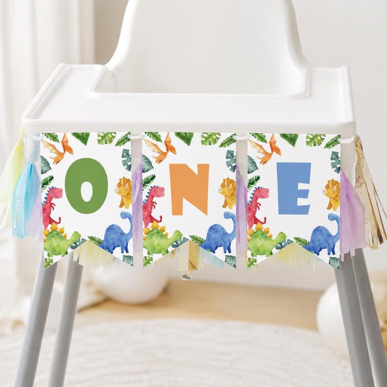 K&ouml;nnte beinhalten: Ein Hochstuhl-Banner bestehend aus drei wei&szlig;en Wimpeln mit Aquarell-Illustrationen von Dinosauriern und tropischen Bl&auml;ttern. Die Buchstaben O, N und E sind in gro&szlig;en gr&uuml;nen, orangen und blauen Schriftarten gedruckt. Mit bunten Quasten.