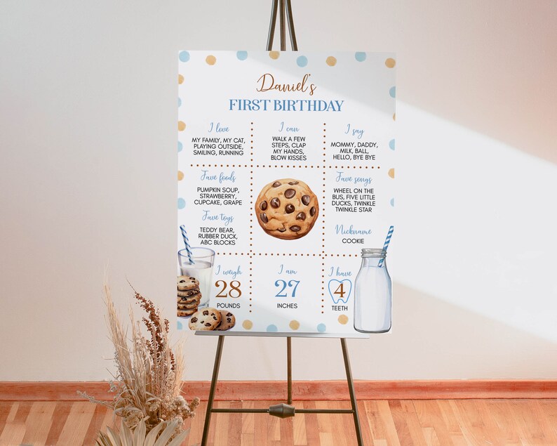 May include: A blue and brown first birthday milestone poster with a cookie theme. The poster includes details about the child's age, weight, height, favorite foods, toys, songs, and words. The poster is decorated with blue and brown polka dots.