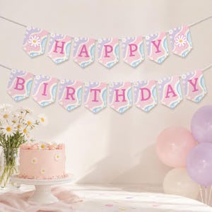 May include: A two-row banner spelling HAPPY BIRTHDAY with pink letters on pennants featuring a wavy light blue, lavender, and white background with daisy patterns. The banner is displayed above a pink cake decorated with white daisies.