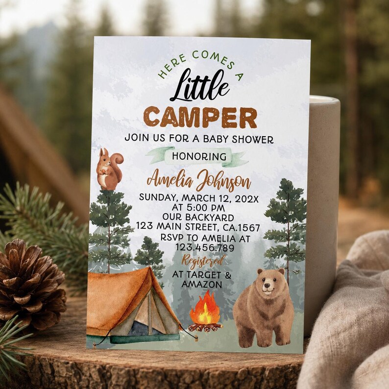 Op de afbeelding: Een rechthoekige uitnodigingskaart voor een babyshower met een aquarel bosthema, een bruine tent, een kampvuur, een eekhoorn en een beer. De tekst luidt: Here Comes A Little Camper, Join Us For A Baby Shower Honoring Amelia Johnson, Sunday, March 12, 202X at 5:00 PM, Our Backyard, 123 Main Street, CA.1567, RSVP to Amelia at 123.456.789, Registered at Target & Amazon.