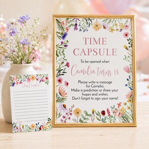 May include: A gold-framed sign and a matching lined card featuring watercolor floral borders. The sign reads: TIME CAPSULE To be opened when Camelia Turns 18. Please write a message for Camelia. Make a prediction or share your hopes and wishes. Don't forget to sign your name!