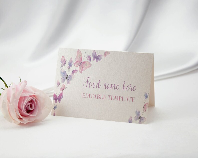 Peut inclure: Une carte pli&eacute;e de couleur cr&egrave;me orn&eacute;e d'aquarelles de papillons dans des tons roses et violets, avec le texte imprim&eacute; Food name here et EDITABLE TEMPLATE, accompagn&eacute;e d'une rose rose p&acirc;le plac&eacute;e sur la gauche de la carte.