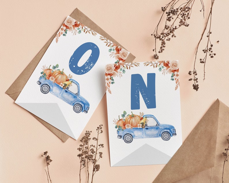 May include: Two white rectangular cards featuring a watercolour illustration of a blue vintage truck carrying orange pumpkins and autumn foliage. The left card displays the blue letter O, and the right card displays the blue letter N in a bold font.