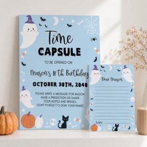 May include: A light blue time capsule sign and matching stationery set featuring Halloween graphics including ghosts, pumpkins, a black cat, bats, and spiderwebs. The text reads Time Capsule to be opened on Mason's 18th Birthday October 30th, 2040.