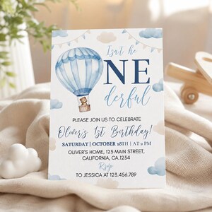 Pu&ograve; includere: Un biglietto d'invito di compleanno rettangolare con una mongolfiera blu ad acquerello e un orsacchiotto nel cestino. Il testo recita: Isn't he ONEderful, PLEASE JOIN US TO CELEBRATE Oliver's 1st Birthday! SATURDAY | OCTOBER 18TH | AT 2 PM.