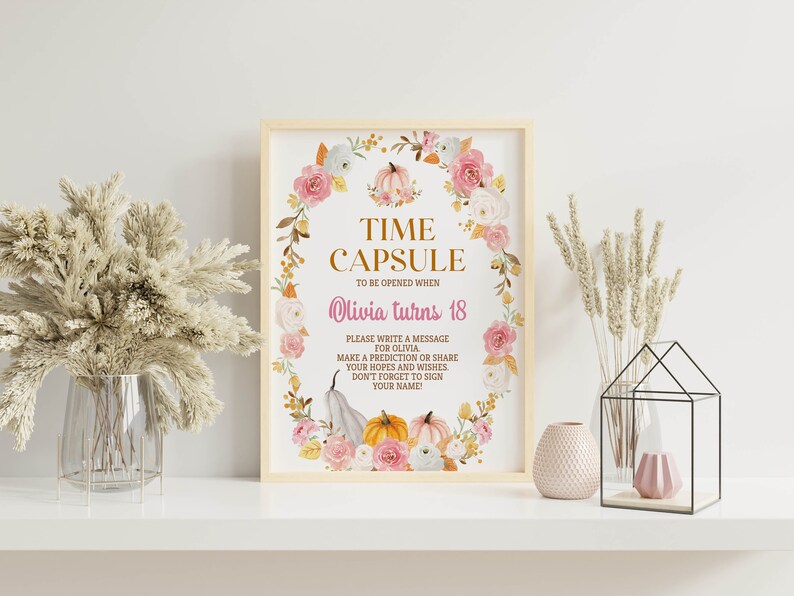 K&ouml;nnte beinhalten: Ein rechteckiges Schild in einem hellen Holzrahmen mit einem Blumenkranz aus rosa Rosen und K&uuml;rbissen. Der Text lautet: TIME CAPSULE TO BE OPENED WHEN Olivia turns 18. PLEASE WRITE A MESSAGE FOR OLIVIA. MAKE A PREDICTION OR SHARE YOUR HOPES AND WISHES.