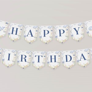 May include: A banner with the words "HAPPY BIRTHDAY" in navy blue letters. Each pennant has a watercolor design of a whale, jellyfish, and coral. The banner is strung on a white string, perfect for a birthday party.