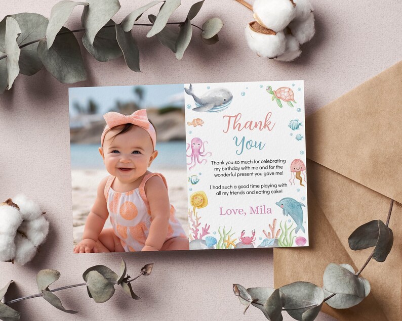 May include: A rectangular thank you card featuring a photograph of a smiling baby wearing a peach bow headband and a patterned romper on the left side, and watercolor illustrations of sea creatures and the text Thank You Love, Mila on the right.